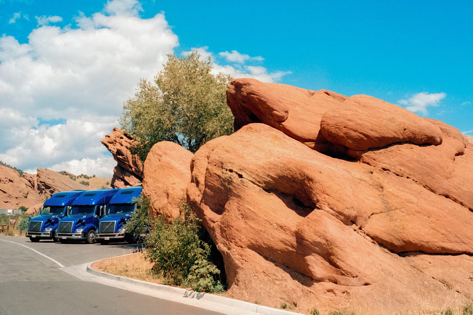 Blue trucks parked next to a rock formation at Red Rocks Park and Amphitheatre